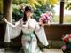 A woman in a kimono holding a bouquet of flowers.