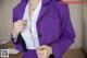 A woman in a purple suit is adjusting her tie.