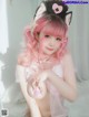 A woman with pink hair wearing a cat ears headband.