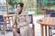 A woman sitting at a table in a trench coat.