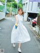 A woman in a white dress is walking down the street.