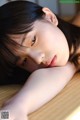 A young woman laying on top of a wooden table.