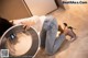 A woman sitting on the floor next to a washing machine.