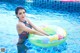 A woman in a bathing suit sitting on an inflatable ring in a pool.