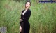 a woman in a black dress standing in tall grass
